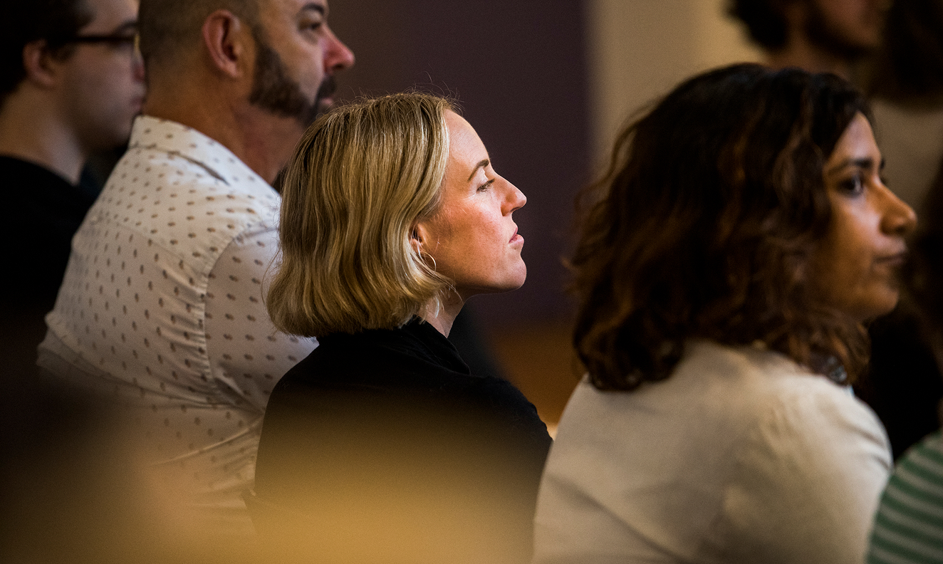 A woman in a seated crowd looking at the stage