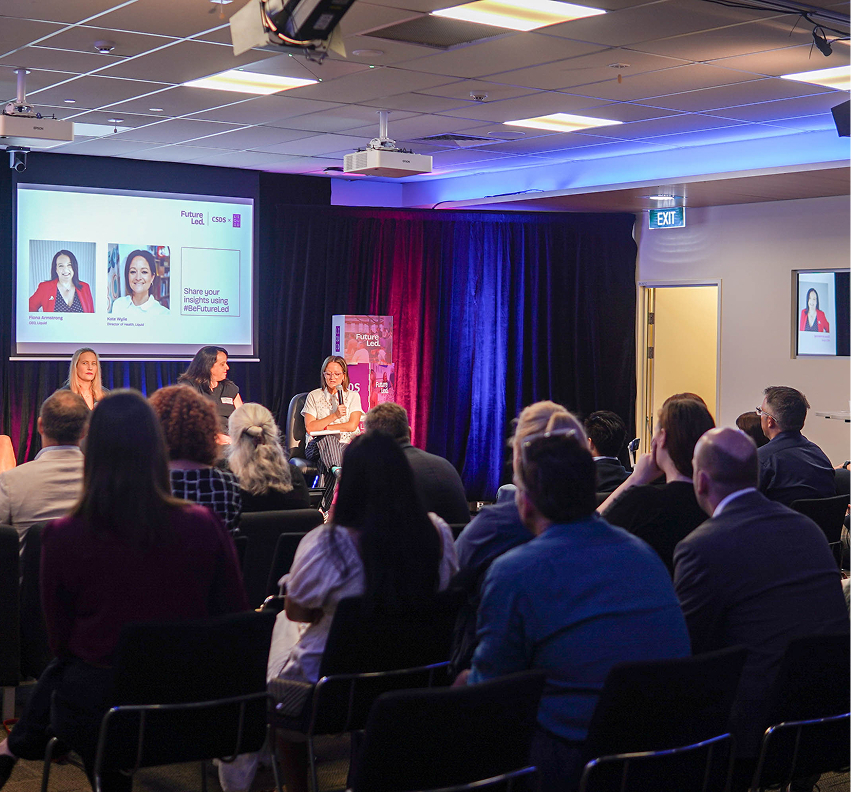 People seated in the audience watching a panel event